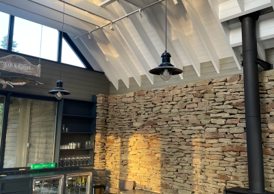 The side of a bar area with brick wall and newly painted high white wooden ceiling area.