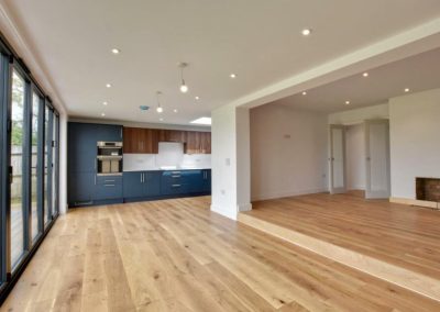 large kitchen area with wooden floors, white walls and blue cabinets.