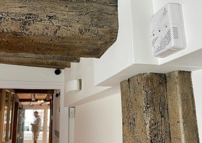 Side angle looking through doors with a decorator in background. There is a newly restored wooden beam in the front of the shot with fresh white paint.
