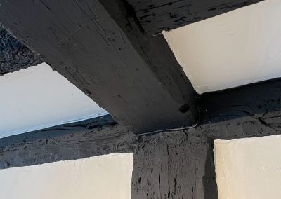 A close up of dark stained old wooden beams on a wall and ceiling