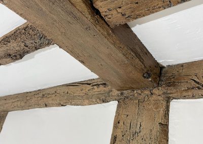 A close up of newly renovated wooden beam with white paintwork surround.