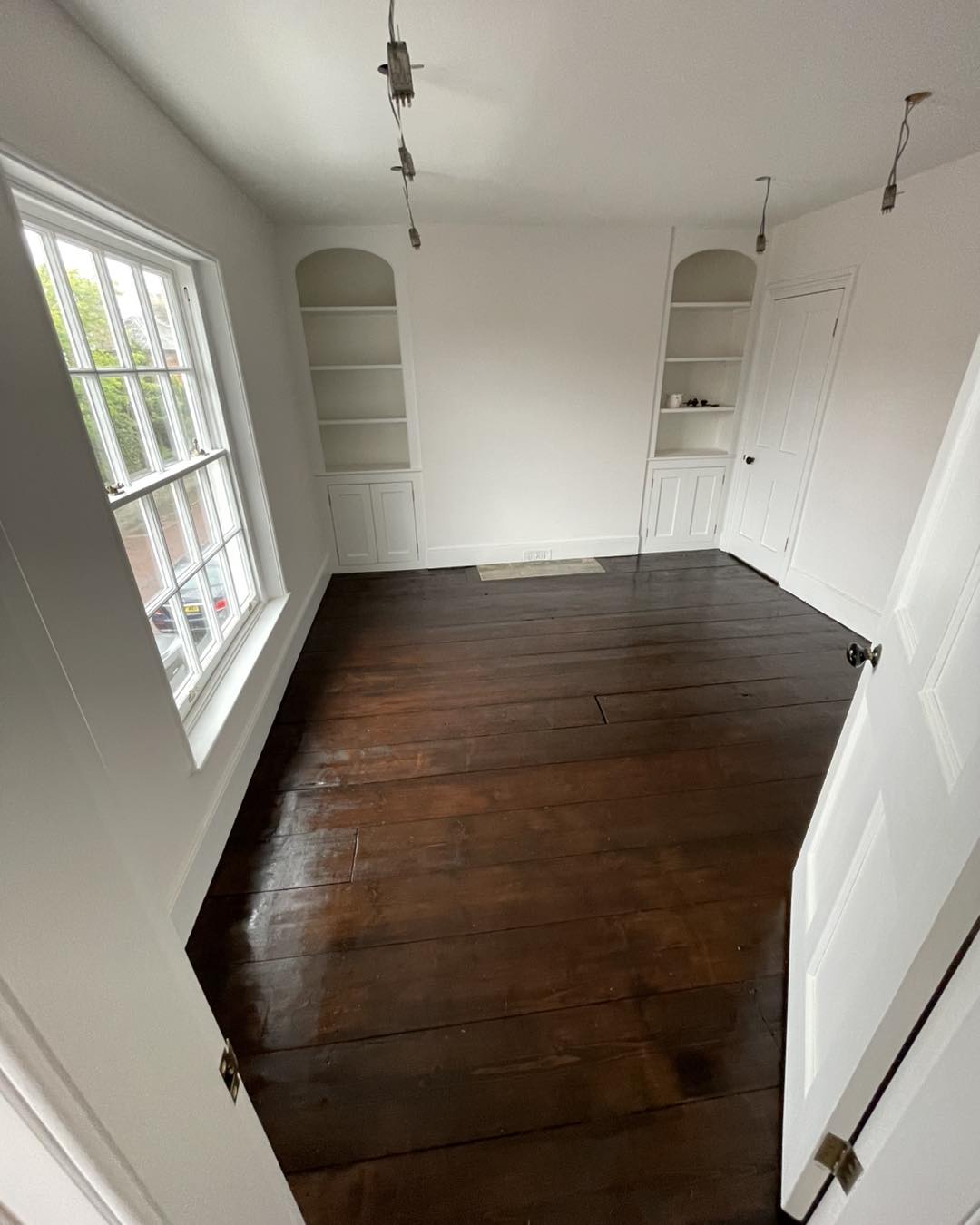 built in cupboard and floor Freshly decorated room with dark wooden floorboards, white painted walls and built-in cupboards on either side of the doorway.