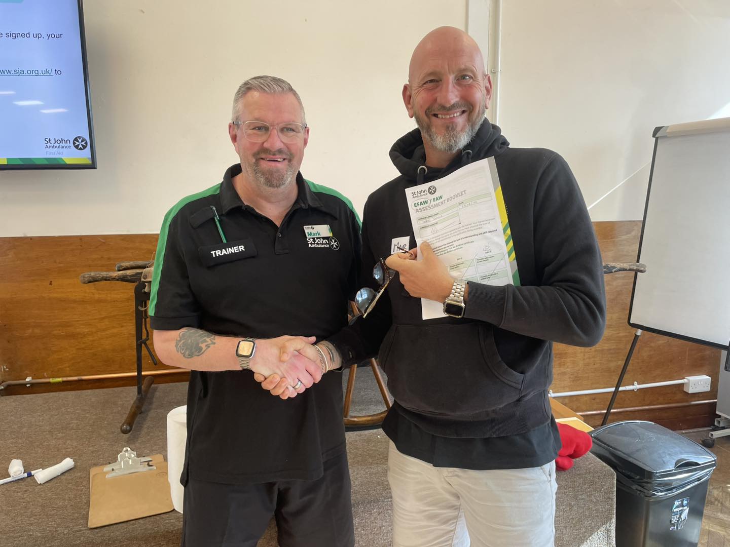 St Johns Ambulance Certification Marc and St. Johns Ambulance trainer shaking hands whilst handing over a certificate.